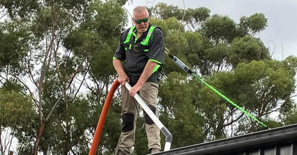 John from Gutter Muncher using professional gutter vacuuming equipment on a roof